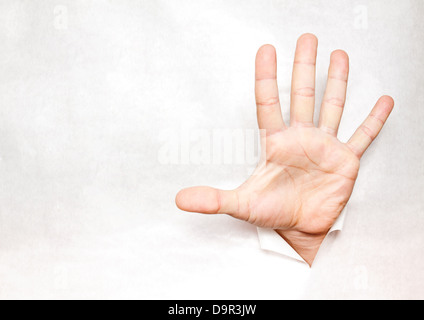 Hand through a hole in paper Stock Photo