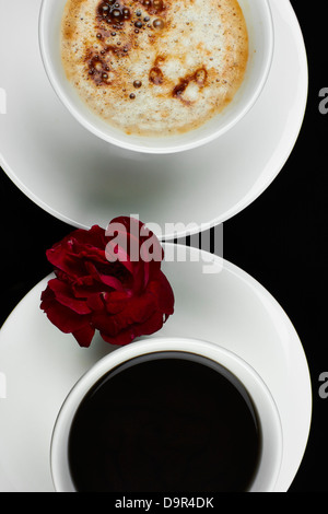 Top view of a red rose between a cup of coffee and tea