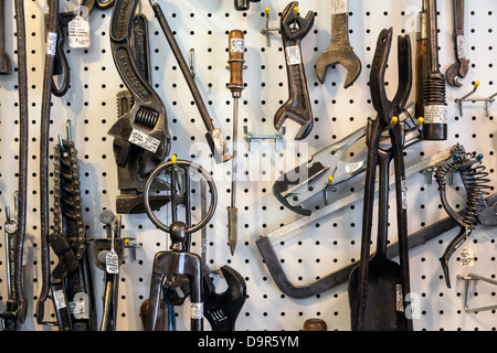 Assorted vintage tools and accessories hanging on a white pegboard. Stock Photo