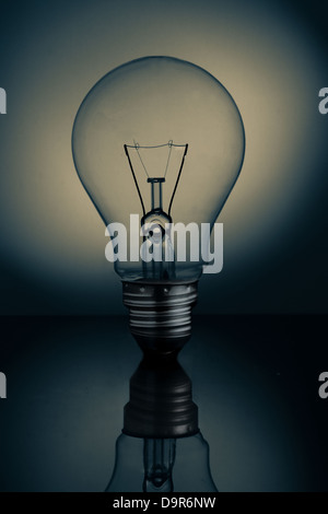 Big clear light bulb standing on reflective surface Stock Photo