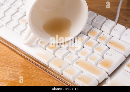 Cup of tea spilled out over a keyboard close up Stock Photo