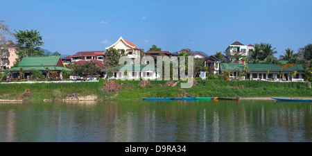 Horizontal panoramic (2 picture stitch) view of the riverside hotels and bars along the Nam Song river in Vang Vieng. Stock Photo