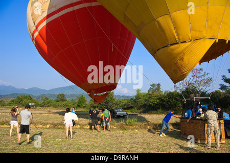 Horizontal view of two hot air balloons in Vang Vieng waiting for lift off with tourists taking photographs. Stock Photo