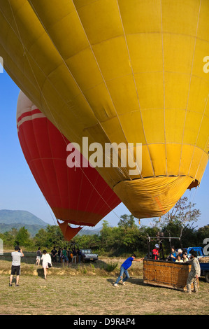 Vertical view of two hot air balloons in Vang Vieng waiting for lift off with tourists taking photographs. Stock Photo