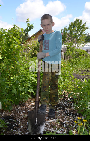 the teenage boy costs with a shovel in a garden Stock Photo