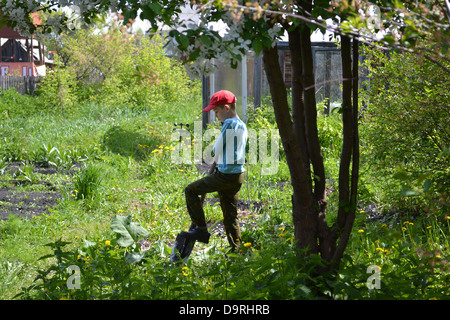 the teenage boy costs with a shovel in a garden Stock Photo