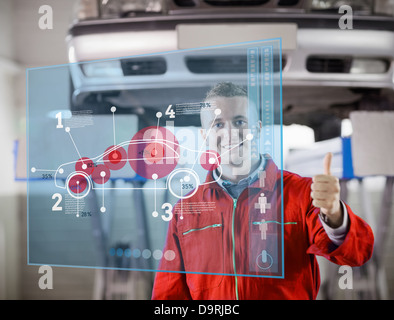 Portrait of smiling mechanic showing thumbs up with futurist interface Stock Photo