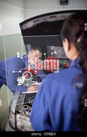 Smiling mechanic looking up at colleague with a futuristic interface Stock Photo