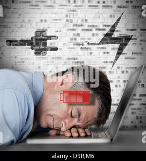 Businessman sleeping on his laptop with low energy and charging symbols Stock Photo