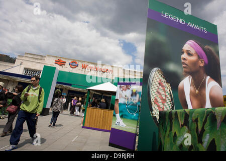 Wimbledon, England, 25th June 2013 - Day 2 of the annual lawn tennis championships and spectators mingle with locals near a large billboard of Ladies champion, Serena Williams seen outside the mainline and underground (subway) station in the south London suburb. The Wimbledon Championships, the oldest tennis tournament in the world, have been held at the nearby All England Club since 1877. Stock Photo