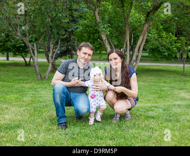 Happy family: mother, father and daughter baby playing in the park Stock Photo