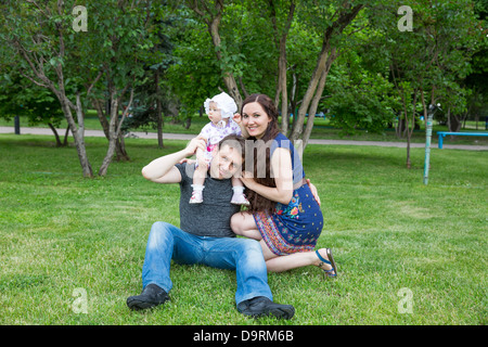 Happy family: mother, father and daughter baby playing in the park Stock Photo