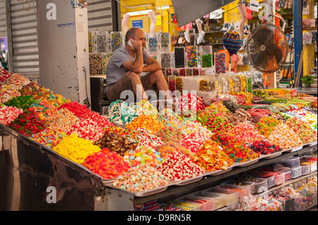 Israel Tel Aviv Carmel Market vendor seller man mobile cell phone iphone penny sweet candy confectionery stall shop store colourful colorful Stock Photo