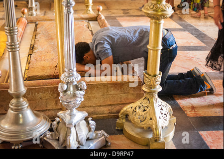 Israel Jerusalem Old City Church of the Holy Sepulcher Stone of the Unction body of Christ anointed wrapped worshipers kneeling in prayer Stock Photo