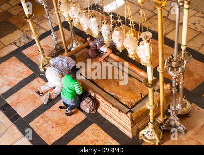 Israel , Jerusalem Old City , Church of the Holy Sepulcher , Stone of the Unction , body of Christ anointed wrapped worshipers kneeling in prayer Stock Photo