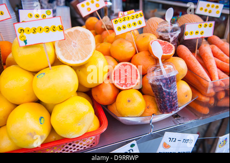Israel Tel Aviv Jaffa Yafo Carmel Market fresh fruit drinks juice stall oranges pink yellow grapefruit citrus carrots pomegranate labels Hebrew Ivrit Stock Photo