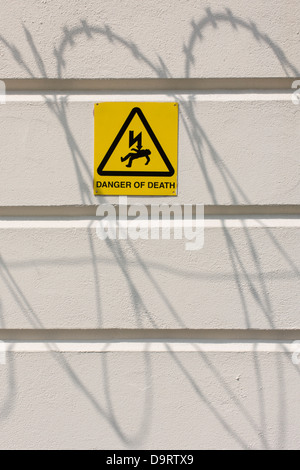 Shadows of razor-wire with a Danger of Death sign, on a white perimeter wall of the All England Lawn Tennis Club, Wimbledon. Stock Photo