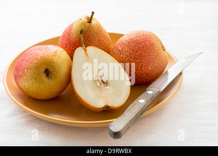 Fresh red pears on plate over light background, selective focus Stock Photo
