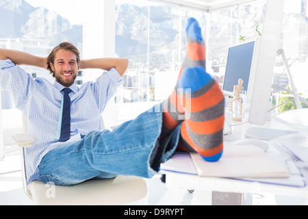 Designer relaxing at desk with no shoes and smiling Stock Photo