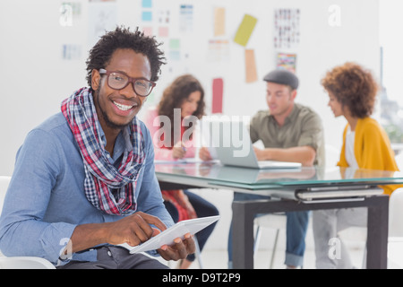 Smiling designer using his tablet pc and looking at camera Stock Photo