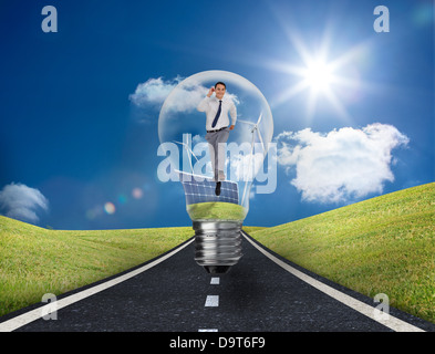 Businessman in light bulb with wind turbines and solar panels Stock Photo