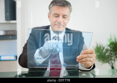 Businessman using futuristic touchscreen to view graph Stock Photo