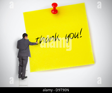 Businessman writing thank you on a giant post it Stock Photo