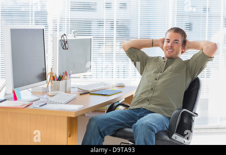 Smiling designer leaning back at his desk Stock Photo