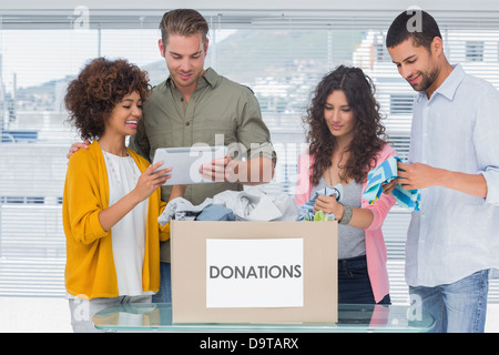 Volunteers using tablet and taking out clothes from a donation box Stock Photo