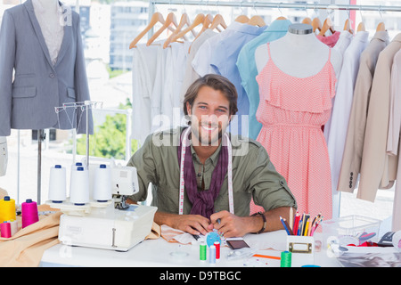 Smiling fashion designer sitting behind a desk Stock Photo