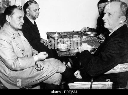 War criminals of the Nazi regime (left to right) Hermann Göring, Alfred Rosenberg, Baldur von Schirach and Karl Dönitz sit at a wooden table with metal plates and pieces of bread during the Nuremberg Trials in 1946.    Photo: Yevgeny Khaldei Stock Photo