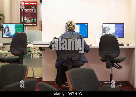 A woman sits a public computer in a council building in the UK Stock Photo