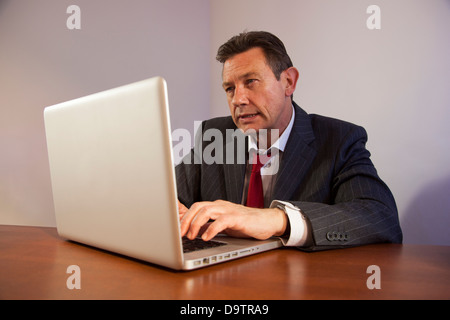 Mature business man at a desk using a laptop computer. Stock Photo