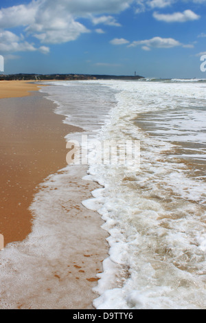 Seafoam waves along the golden sandy shored beach of Praia da Rocha in Algarve, Portugal Stock Photo