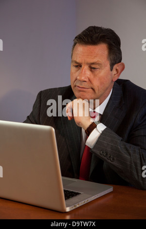 Mature business man at a desk using a laptop computer. Stock Photo