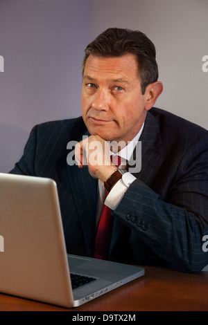 Portrait business man at a desk looking to camera with laptop. Stock Photo