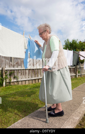 Ninety year old woman, pensioner with walking/zimmer frame checking washing on line. UK Stock Photo