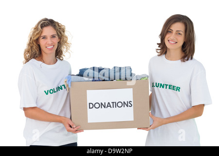 Two cheerful volunteers carrying clothes donation box Stock Photo