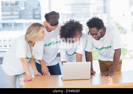 Smiling volunteers working together on a laptop Stock Photo