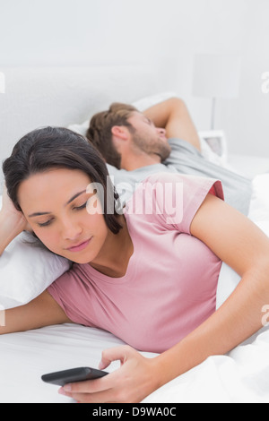 man texting message while woman is sleeping in bed Stock Photo - Alamy