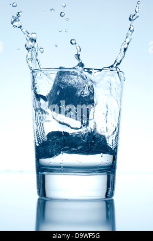 Ice cube falling into glass of water Stock Photo - Alamy