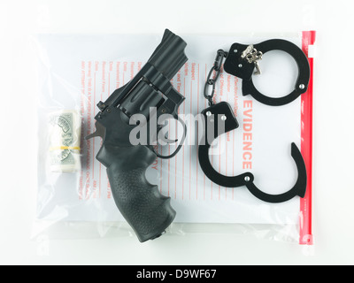 aerial view of a bag marked evidence containing a roll of money, a revolver and a pair of handcuffs with their keys, on a white background Stock Photo