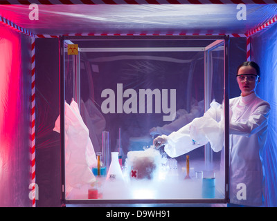 woman scientist conducting experiment with a steaming substance in a protection enclosure, in a containment tent Stock Photo