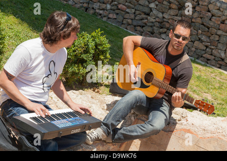 young men playing music in summer sunshine outside Stock Photo