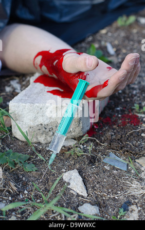 Bloody hand and syringe near it. Crime scene Stock Photo