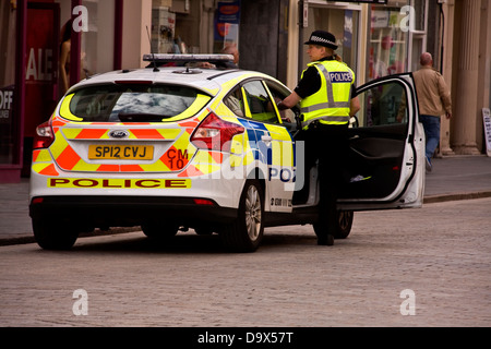 Woman Police Officer stepping into a Police car after investigating a scene inside a High Street Retail store in Dundee, UK Stock Photo