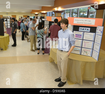 Students displaying and explaining posters of their science research projects at a science symposium/ science fair Stock Photo