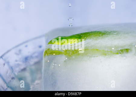 Water drops falling on a green chili pepper frozen in an ice cube Stock Photo