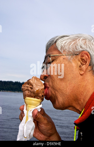 Chinese man eating 'baby' chocolate peanut butter chunk ice cream cone Discovery Fishing Pier food concession stand Stock Photo
