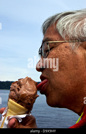 Chinese man eating 'baby' size chocolate peanut butter chunk ice cream cone Discovery Fishing Pier food concession stand Stock Photo